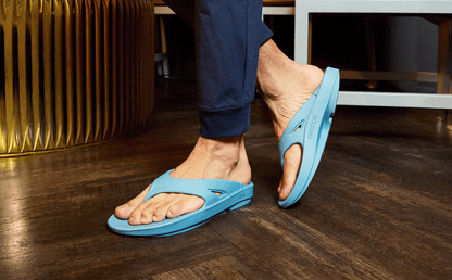 Person wearing blue sandals on a wooden floor