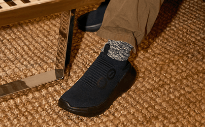 Men's OOmy Zen - Black close up of shoe on model sitting inside | lifestyle