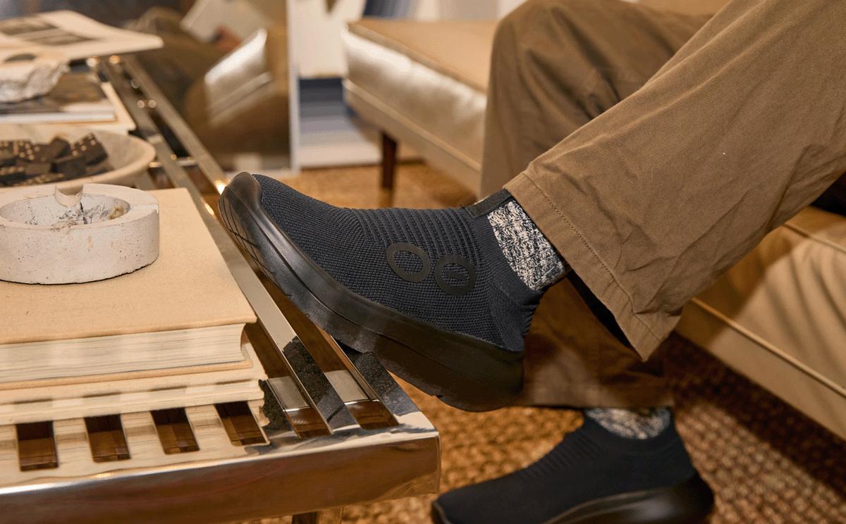 Men's OOmy Zen - Black shoe on model sitting on couch resting foot on coffee table | lifestyle